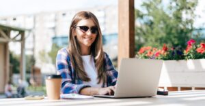 Woman wearing sunglasses using a laptop outside