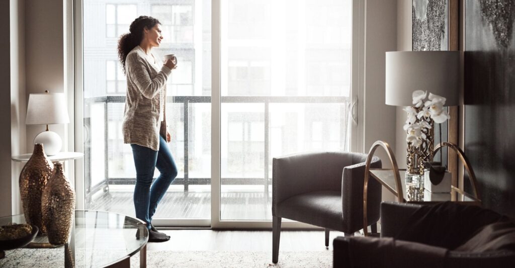 Woman holding a mug and smiling by a window