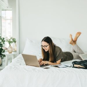 Woman using a laptop while lying on a bed