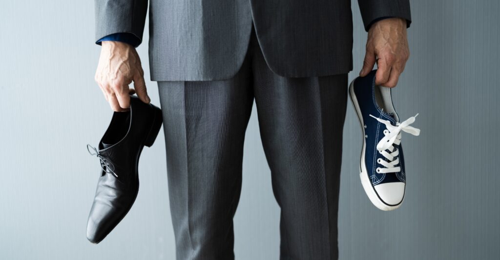 Man in suit holding tennis shoe and dress shoe