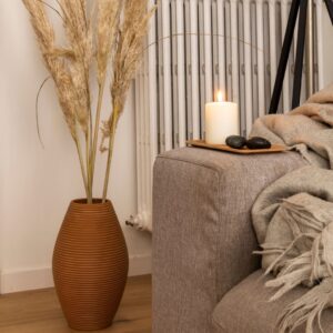 candle and orange vase next to couch