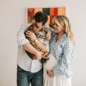 family expecting a baby and holding a cat