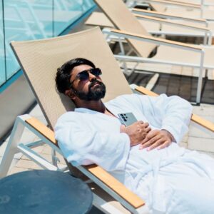 man relaxing in robe next to pool